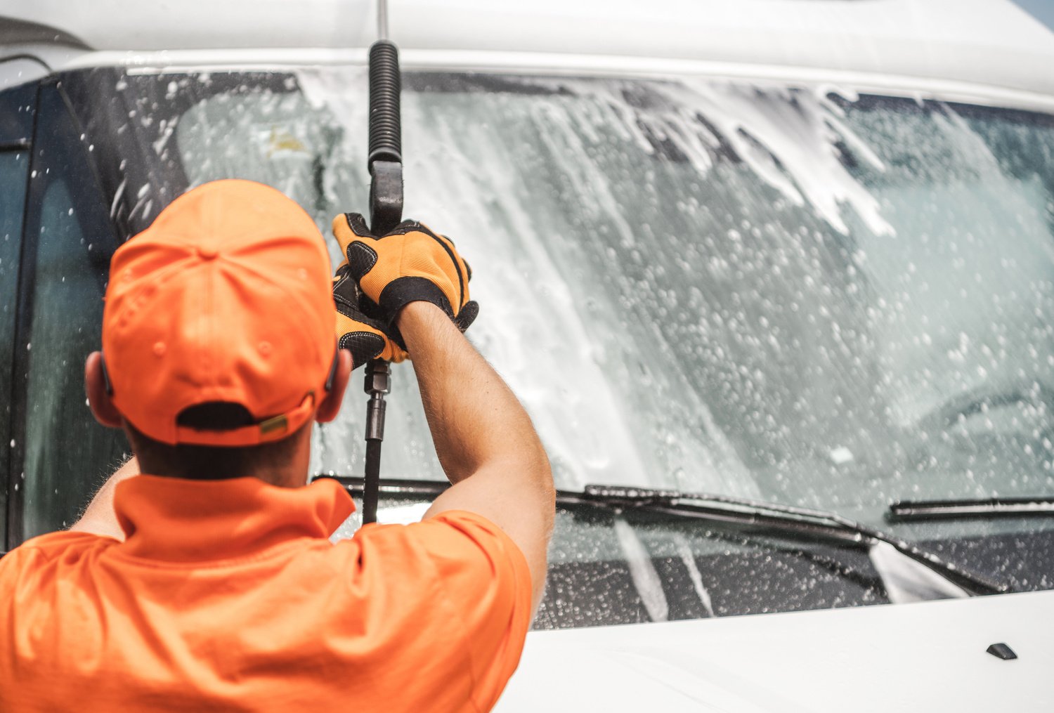 Man Pressure Washing a Van's Windshield