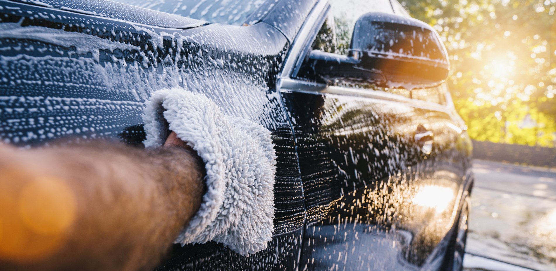 Man Worker Washing Black SUV with Sponge on a Car Wash.